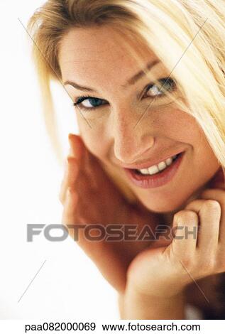 Stock Photo - Woman with hands around face, looking at camera, portrait.. Fotosearch