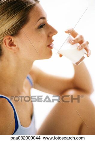 Picture - Woman with knee up, drinking, partial side view.. Fotosearch