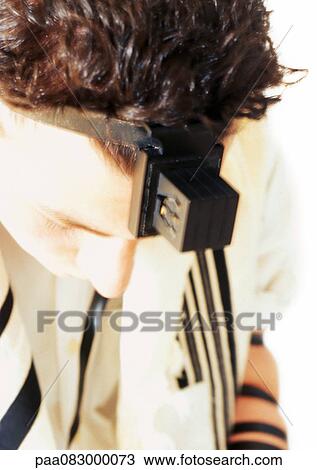 Stock Image - Close up of Jewish man wearing Tefillin for prayer, close-up. Fotosearch