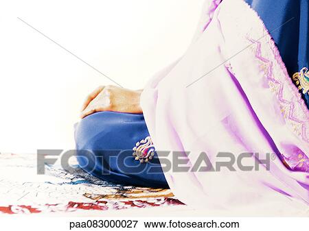 Stock Photo - Muslim woman sitting on prayer rug. Fotosearch