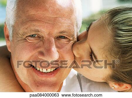 Stock Image - Girl kissing mature man on cheek, close-up. Fotosearch