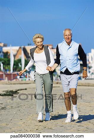 Mature couple holding hands walking on beach, front view, full length View Large Photo Image Stock Photo - Mature couple holding hands walking on beach, front view, full length. Fotosearch