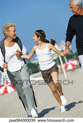 Mature couple holding hands with girl on the beach. View Large Photo Image Stock Photo - Mature couple holding hands with girl on the beach.. Fotosearch