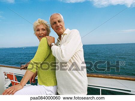 Stock Image - Mature couple standing together next to rail on boat deck.. Fotosearch