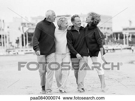 Picture - Mature couples walking on beach, B&W.. Fotosearch