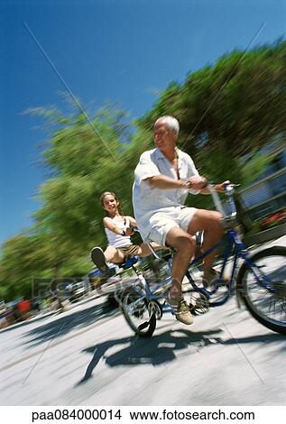 Mature man and girl riding bikes, blurred motion View Large Photo Image Picture - Mature man and girl riding bikes, blurred motion. Fotosearch