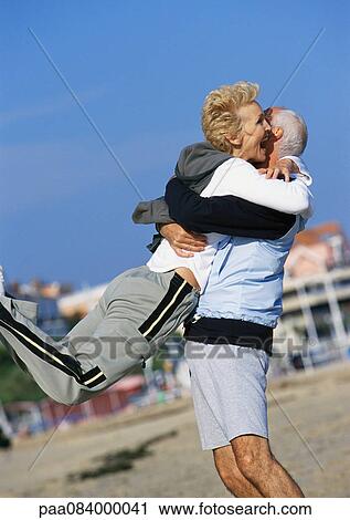 Mature man swinging mature woman on beach. View Large Photo Image Stock Image - Mature man swinging mature woman on beach.. Fotosearch