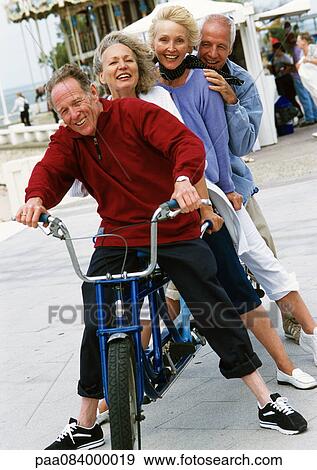 Stock Photo - Mature men and women on stationary tandem bike, portrait.. Fotosearch