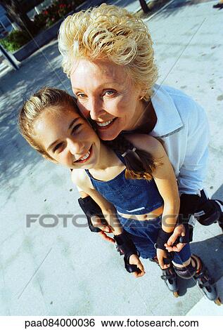 Stock Photograph - Mature woman and young girl on in line skates, smiling, high angle view. Fotosearch
