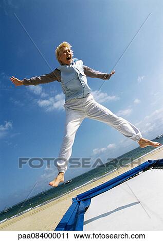 Mature woman jumping on trampoline at the beach. View Large Photo Image Stock Image - Mature woman jumping on trampoline at the beach.. Fotosearch