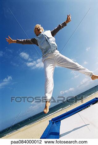 Mature woman jumping on trampoline at the beach. View Large Photo Image Stock Image - Mature woman jumping on trampoline at the beach.. Fotosearch