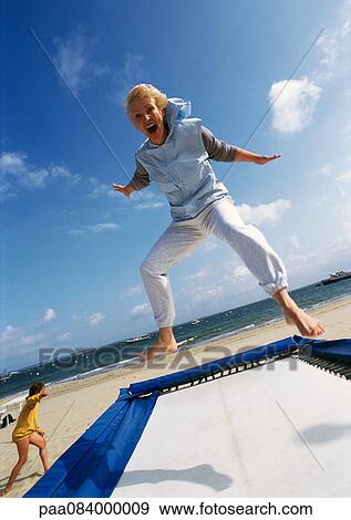 Mature woman jumping on trampoline at the beach. View Large Photo Image Stock Photo - Mature woman jumping on trampoline at the beach.. Fotosearch