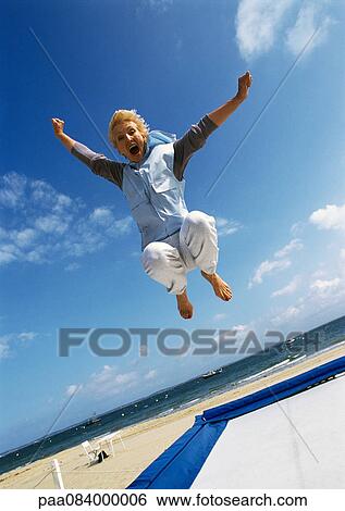 Mature woman jumping on trampoline at beach View Large Photo Image Stock Photograph - Mature woman jumping on trampoline at beach. Fotosearch