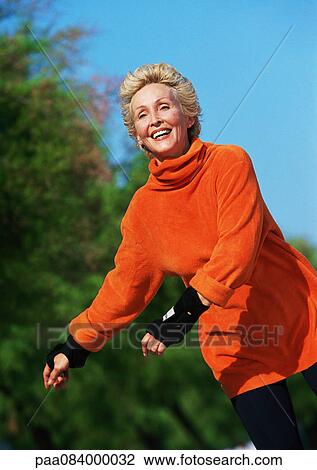 Stock Image - Mature woman smiling, in-line skating.. Fotosearch