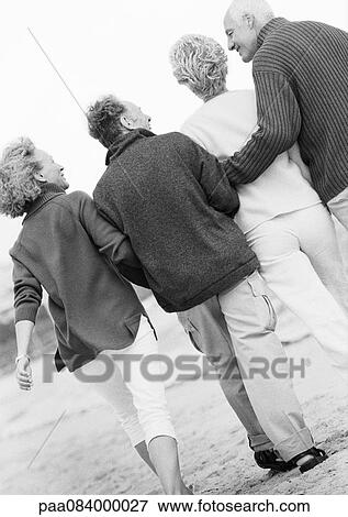 Stock Photo - Two mature couples walking down the beach together, view from above, B&W.. Fotosearch
