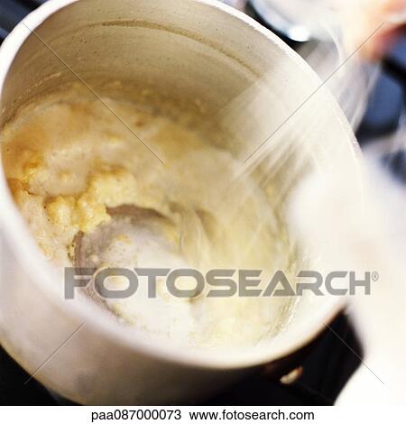 Stock Image - Close-up of bechamel sauce being cooked in a pot. Fotosearch