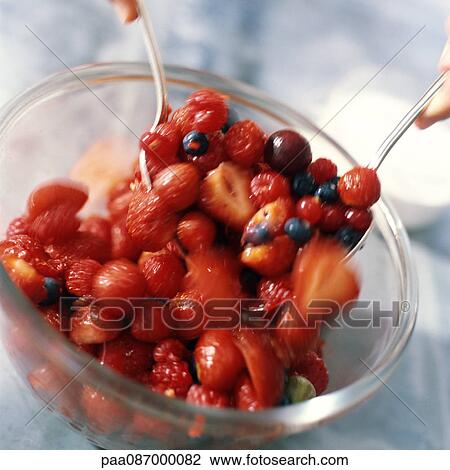 Stock Image - Close-up of bowl of berries being mixed.. Fotosearch