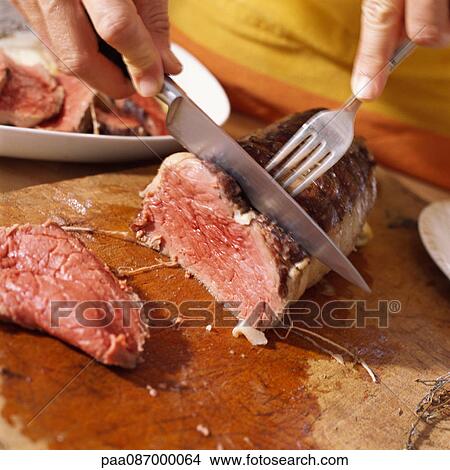 Close-up of hands cutting roast beef View Large Photo Image Picture - Close-up of hands cutting roast beef. Fotosearch
