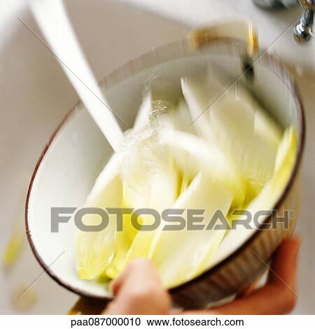 Stock Image - Endives being rinsed off in colander, close-up. Fotosearch