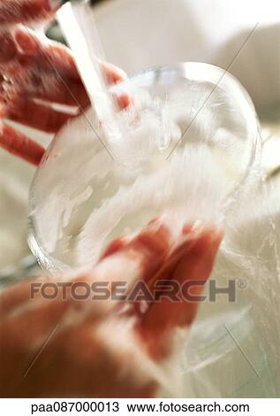 Stock Image - Hands washing dish, close-up. Fotosearch