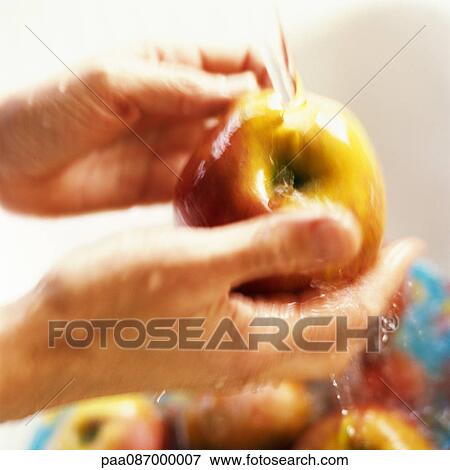 Stock Photo - Person washing apples, close-up, blurry.. Fotosearch