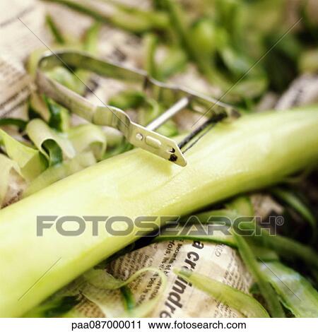 Stock Image - Vegetable peeler, peeled cucumber and peelings, close-up. Fotosearch