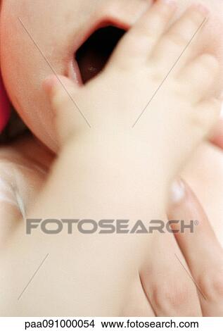 Picture - Baby covering mouth, close-up. Fotosearch