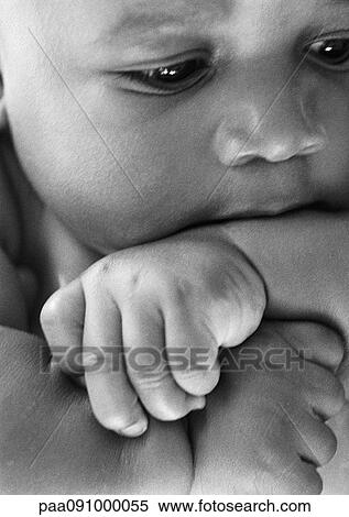 Stock Photography - Baby with arm in mouth, close-up, b&w. Fotosearch