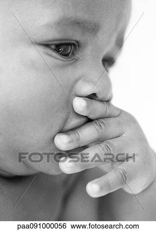 Stock Photograph - Baby with hand over mouth, close-up, b&w. Fotosearch