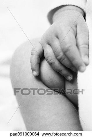 Picture - Baby's hand on leg, close-up. Fotosearch