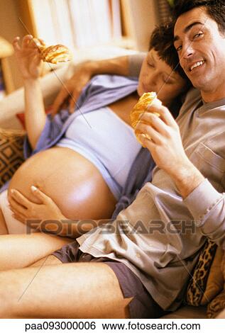 Man and pregnant woman eating croissants on sofa View Large Photo Image Stock Photograph - Man and pregnant woman eating croissants on sofa. Fotosearch