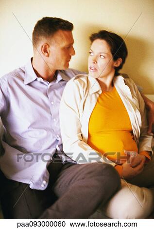Stock Image - Man and pregnant woman sitting and looking at each other. Fotosearch