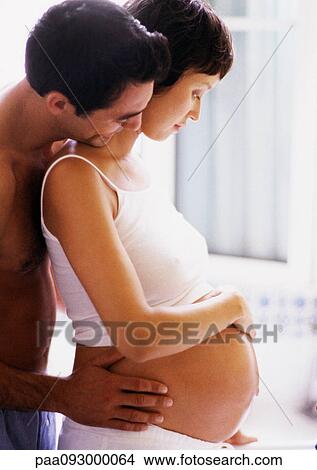 Man holding pregnant woman's waist and looking over her shoulder, side view View Large Photo Image Picture - Man holding pregnant woman's waist and looking over her shoulder, side view. Fotosearch