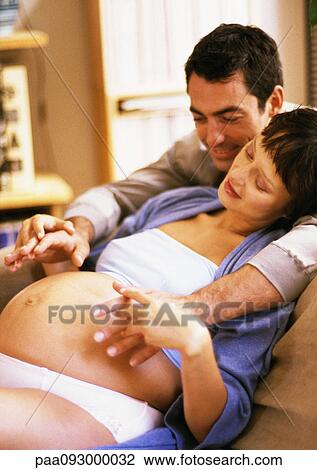 Man looking at pregnant woman's stomach, holding her hands View Large Photo Image Stock Image - Man looking at pregnant woman's stomach, holding her hands. Fotosearch