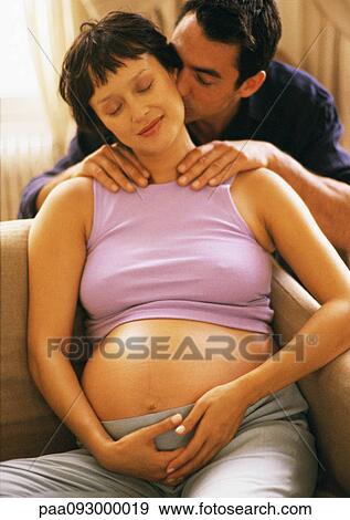 Stock Photo - Man massaging pregnant woman's shoulders, kissing her neck. Fotosearch