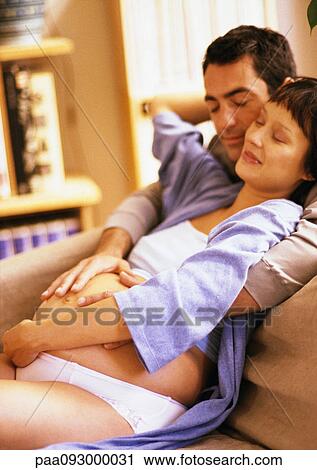 Stock Image - Man touching pregnant woman's stomach from behind. Fotosearch