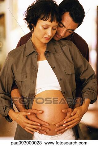 Man touching pregnant woman's stomach from behind View Large Photo Image Stock Photo - Man touching pregnant woman's stomach from behind. Fotosearch