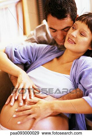 Stock Photo - Man touching pregnant woman's stomach from behind. Fotosearch