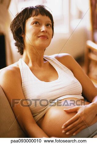 Pregnant woman in armchair, hand on belly and looking up View Large Photo Image Stock Image - Pregnant woman in armchair, hand on belly and looking up. Fotosearch