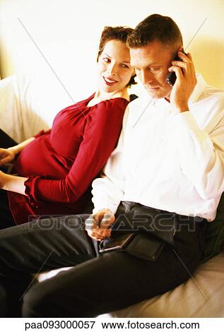 Pregnant woman leaning against man talking on cell phone View Large Photo Image Stock Photo - Pregnant woman leaning against man talking on cell phone. Fotosearch