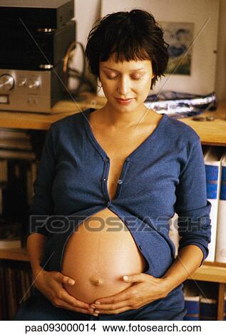 Pregnant woman looking at her stomach View Large Photo Image Picture - Pregnant woman looking at her stomach. Fotosearch