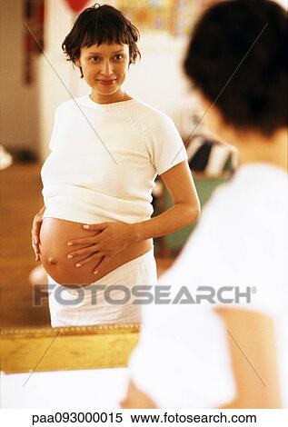 Pregnant woman looking at herself in mirror View Large Photo Image Stock Photography - Pregnant woman looking at herself in mirror. Fotosearch