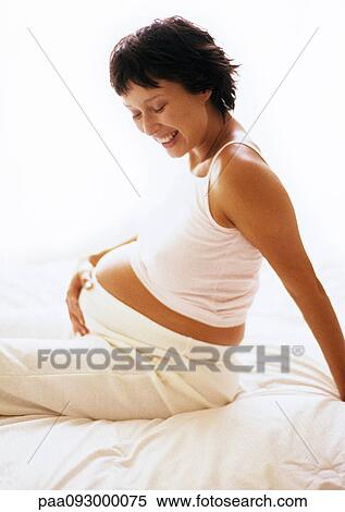 Pregnant woman sitting with hand on stomach, smiling View Large Photo Image Stock Photography - Pregnant woman sitting with hand on stomach, smiling. Fotosearch