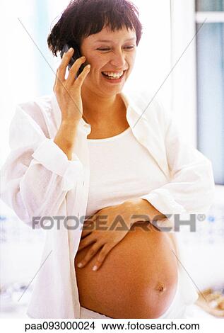 Picture - Pregnant woman using cell phone, smiling. Fotosearch