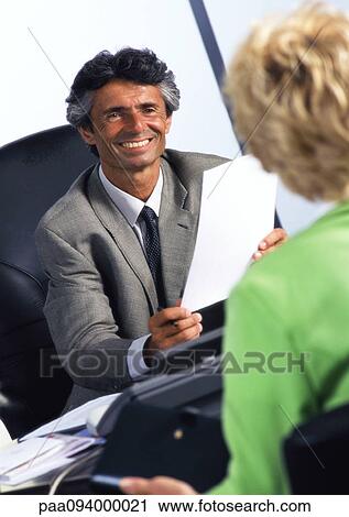 Businessman at desk, smiling at woman View Large Photo Image Stock Image - Businessman at desk, smiling at woman. Fotosearch