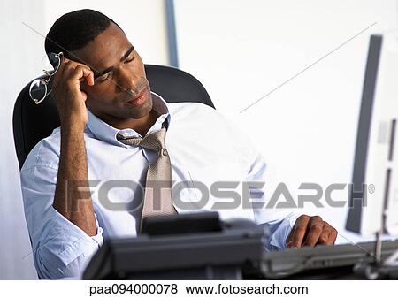 Businessman sitting at desk with eyes closed View Large Photo Image Stock Photo - Businessman sitting at desk with eyes closed. Fotosearch