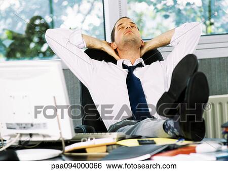 Businessman sitting with feet on desk, hands behind neck and eyes closed View Large Photo Image Stock Photograph - Businessman sitting with feet on desk, hands behind neck and eyes closed. Fotosearch