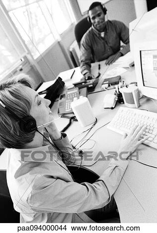 Businesswoman and colleague wearing headsets, B&W View Large Photo Image Picture - Businesswoman and colleague wearing headsets, B&W. Fotosearch