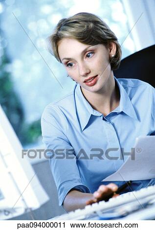 Businesswoman holding document, looking at computer View Large Photo Image Stock Image - Businesswoman holding document, looking at computer. Fotosearch
