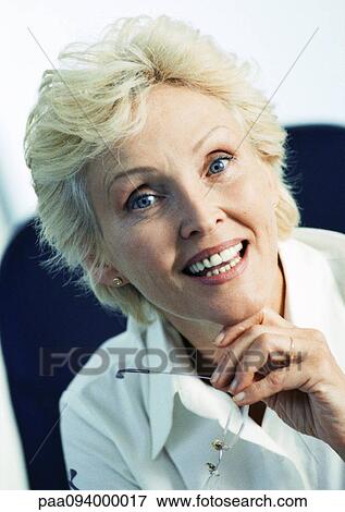 Businesswoman holding glasses, smiling at camera, portrait View Large Photo Image Stock Photo - Businesswoman holding glasses, smiling at camera, portrait. Fotosearch